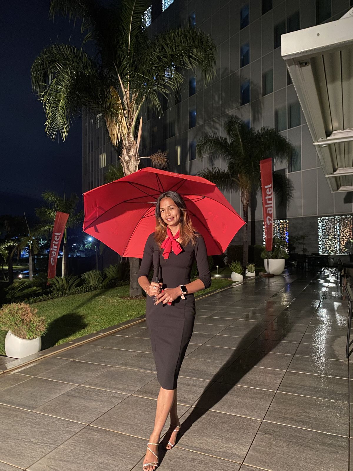 Accueil en soirée — Hôtesse en tenue de soirée, parapluie rouge.